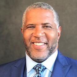 Headshot of Robert F. Smith ‘94 wearing a white collared button-down shirt and a blue suit jacket