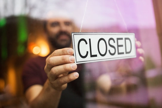 a man hangs a closed sign in the window of a store
